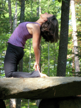 Marisha in a yoga pose on a rock in the forest